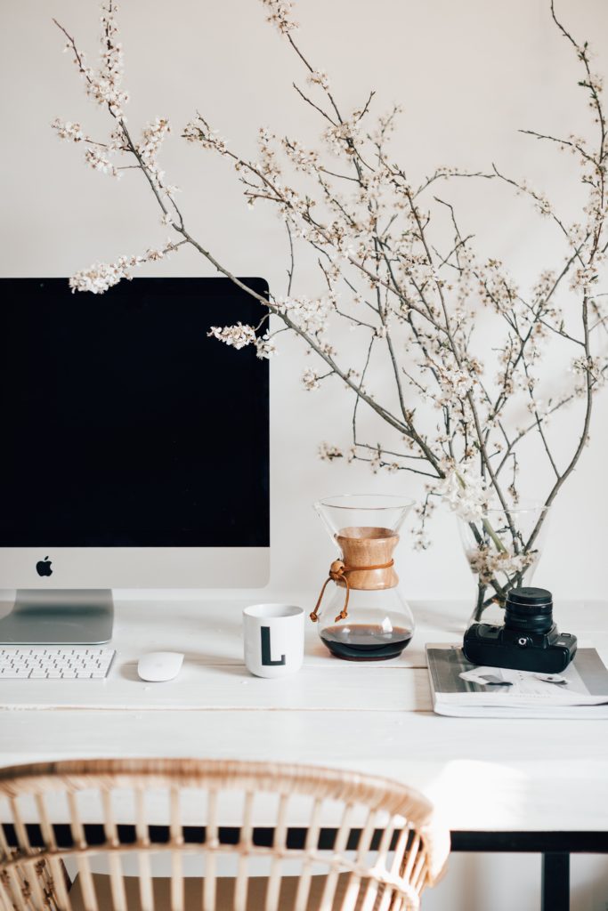 An image of an organized desk with a computer, coffee, and a camera.